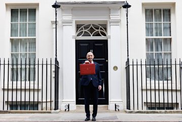 Image shows Chancellor John Healey holding the red Budget briefcase outside Number 11