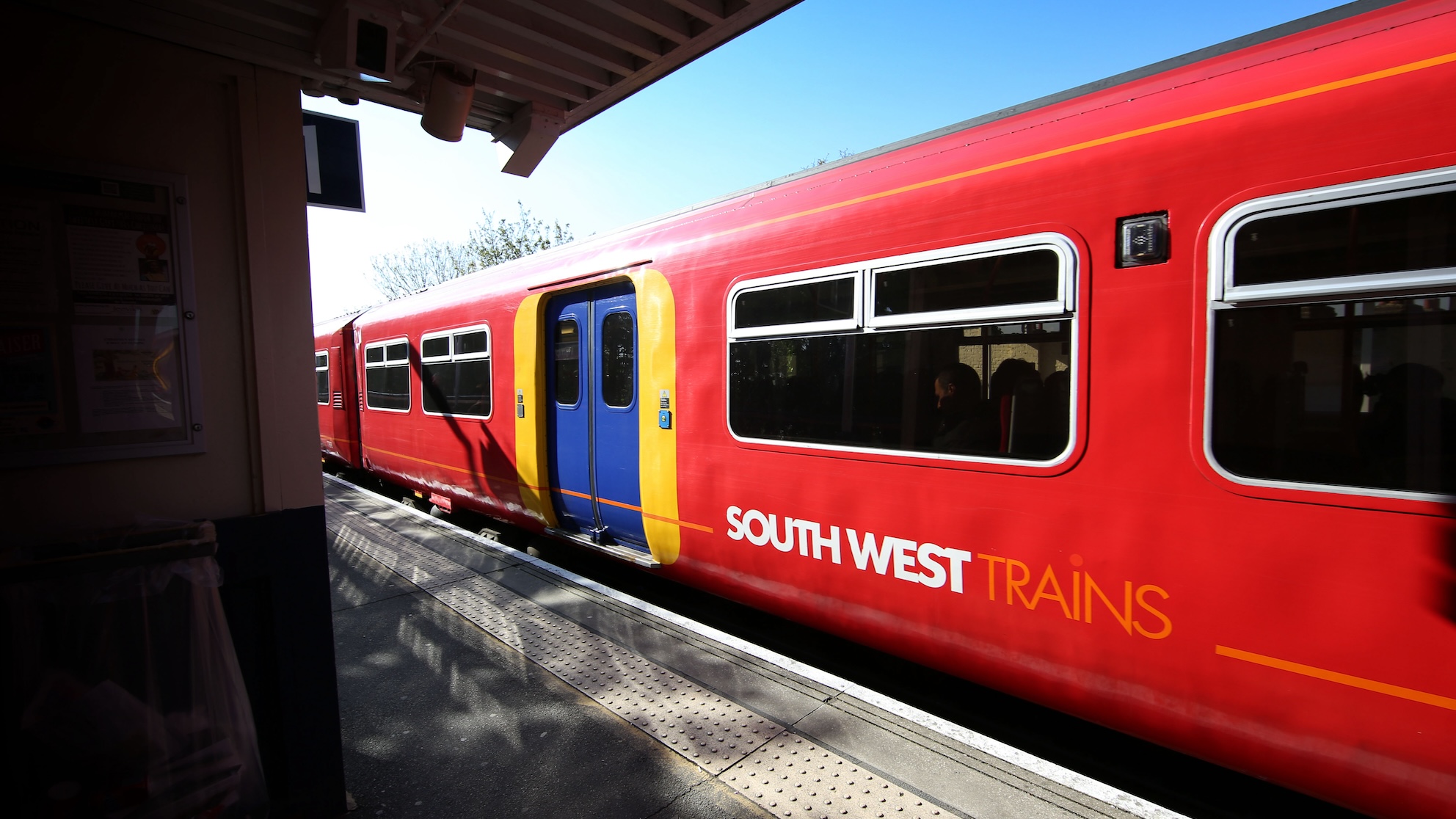 Red South West Trains carriage with blue door waiting at platform