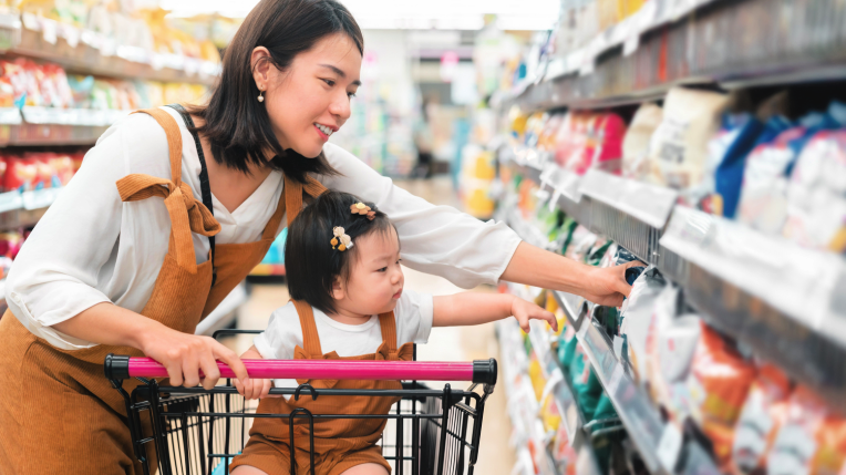 A mother grocery shopping with her baby