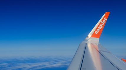 View from Easyjet aeroplane window showing the plane's wing against a blue sky