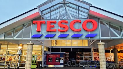 A Tesco storefront with a pointed roof and large glass windows