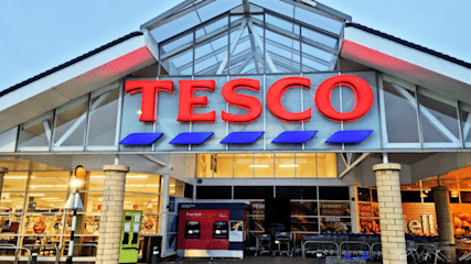 A Tesco storefront with a pointed roof and large glass windows