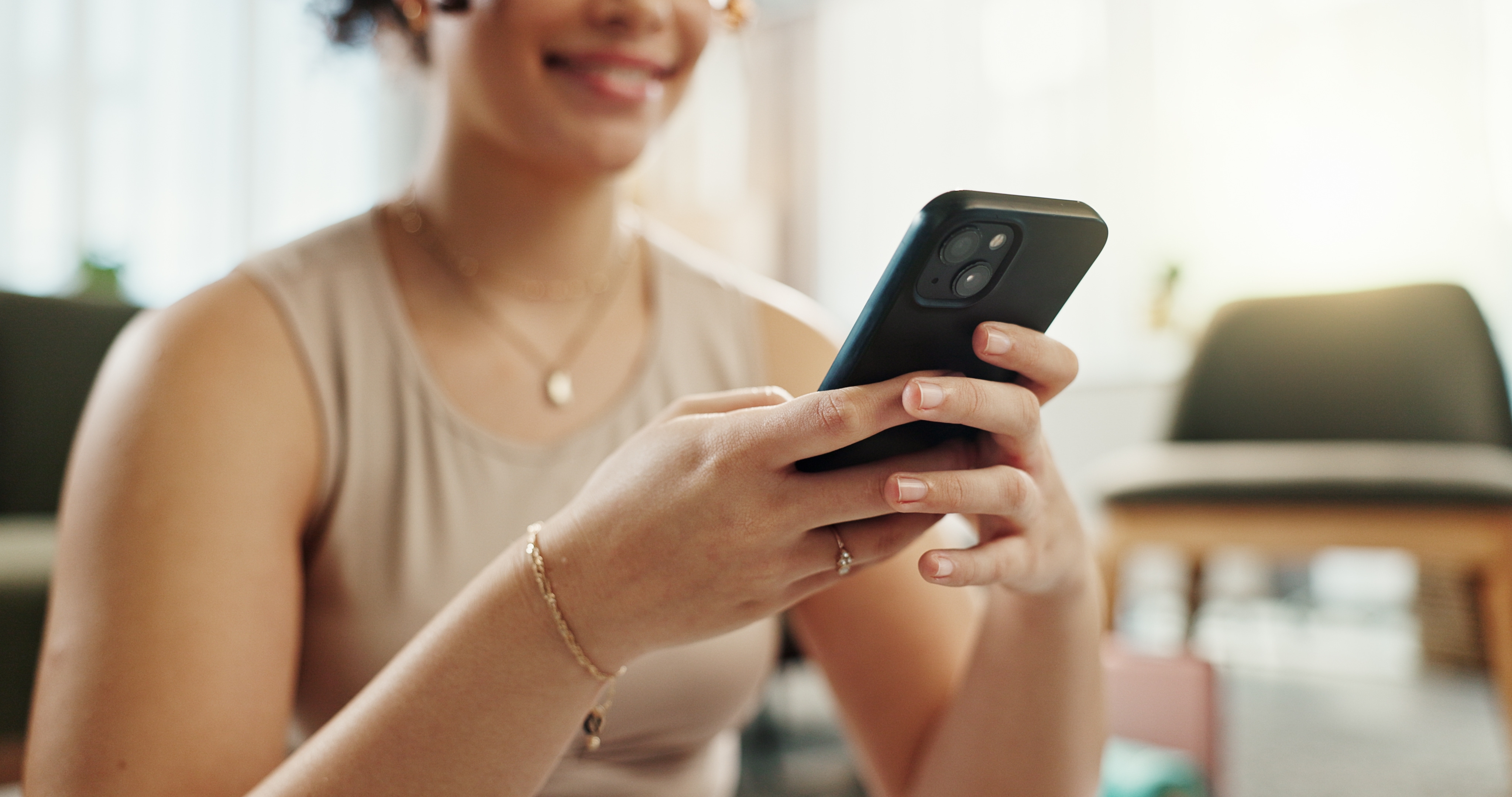 Woman smiling while holding a mobile phone. 