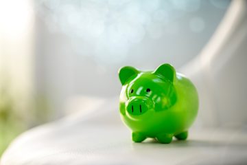 Green piggybank perched on a surface.