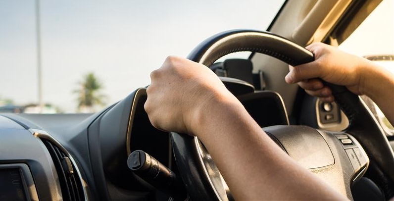 Two hands on a car stirring wheel