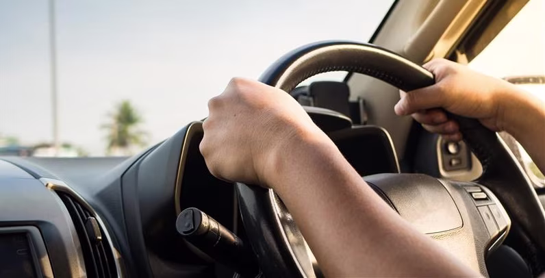 Two hands on a car stirring wheel