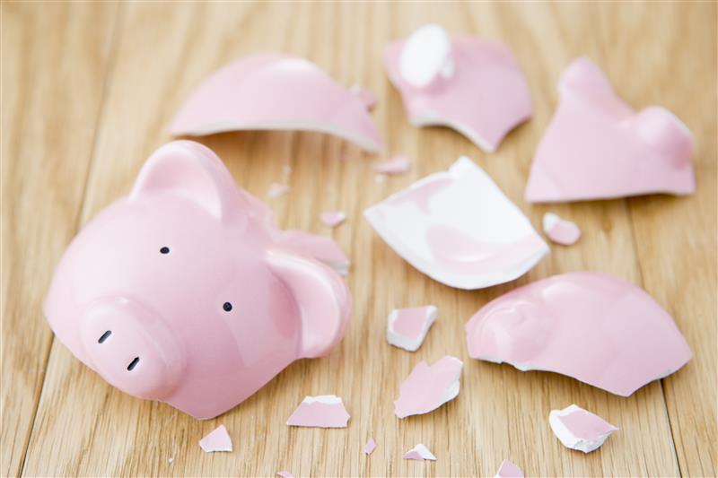 A pink piggy bank shattered on a hardwood floor