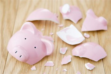 A pink piggy bank shattered on a hardwood floor