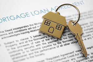 Miniature house on a set of keys on top of a mortgage loan agreement