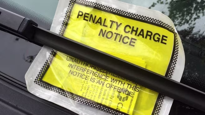 Yellow parking ticket left under a windscreen wiper, which reads