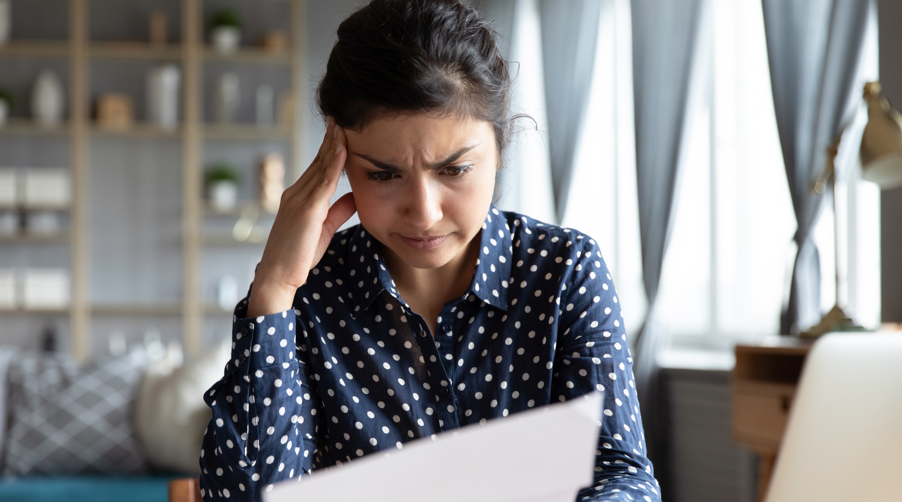 Woman going through paperwork with laptop open next to her