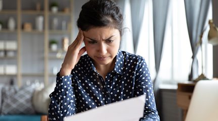 Woman going through paperwork with laptop open next to her