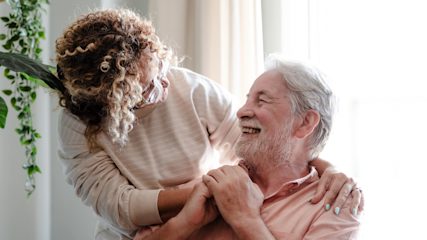 Older man smiling warmly as he is comforted by a relative