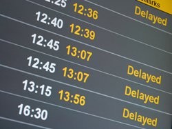 A close-up of an airport departure board, with a series of times and the word "delayed" several times across it.
