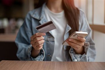 A woman holding a mobile phone and a credit card