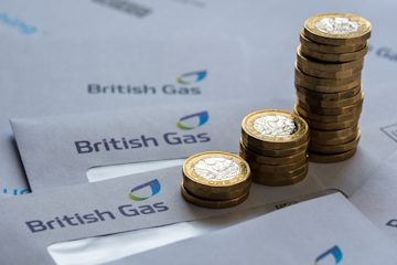 Stacks of pound coins sitting on a pile of envelopes, all with the British Gas logo
