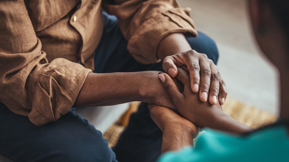 A young woman holding an old man's hands
