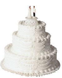 A white three-tiered wedding cake with a bridge and groom figuring on top.