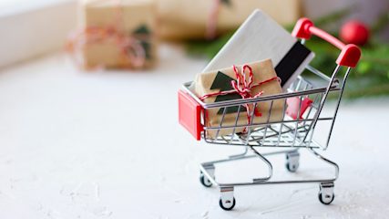 Miniature shopping trolley with wrapped Christmas gift and credit card inside