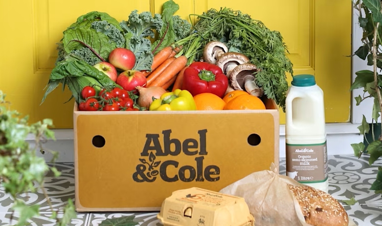 A box of fruit and vegetables with the brand name 'Abel & Cole' displayed on the front. 
