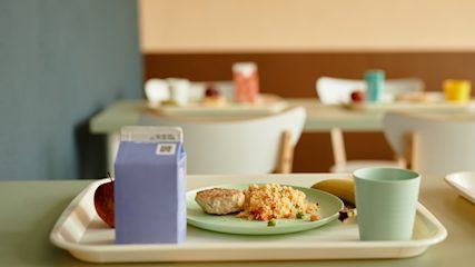 Plastic tray with plate of food and juice box on a canteen table