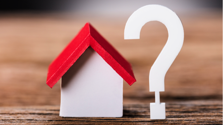 Model of a wooden house with a question mark next to it