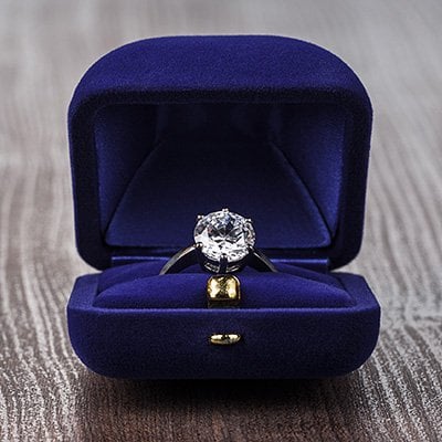 An engagement ring in a blue velvet box.