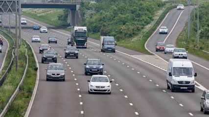 Cars, vans and lorries travelling along a busy UK motorway, with traffic joining from a slip road on the right