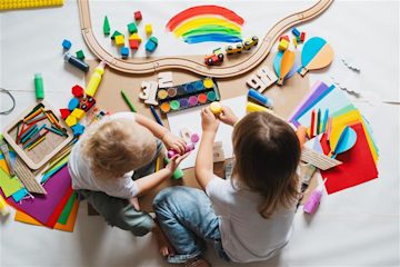 Two children doing arts and crafts on the floor.