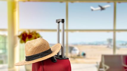 A summer hat on top of a suitcase at the airport.