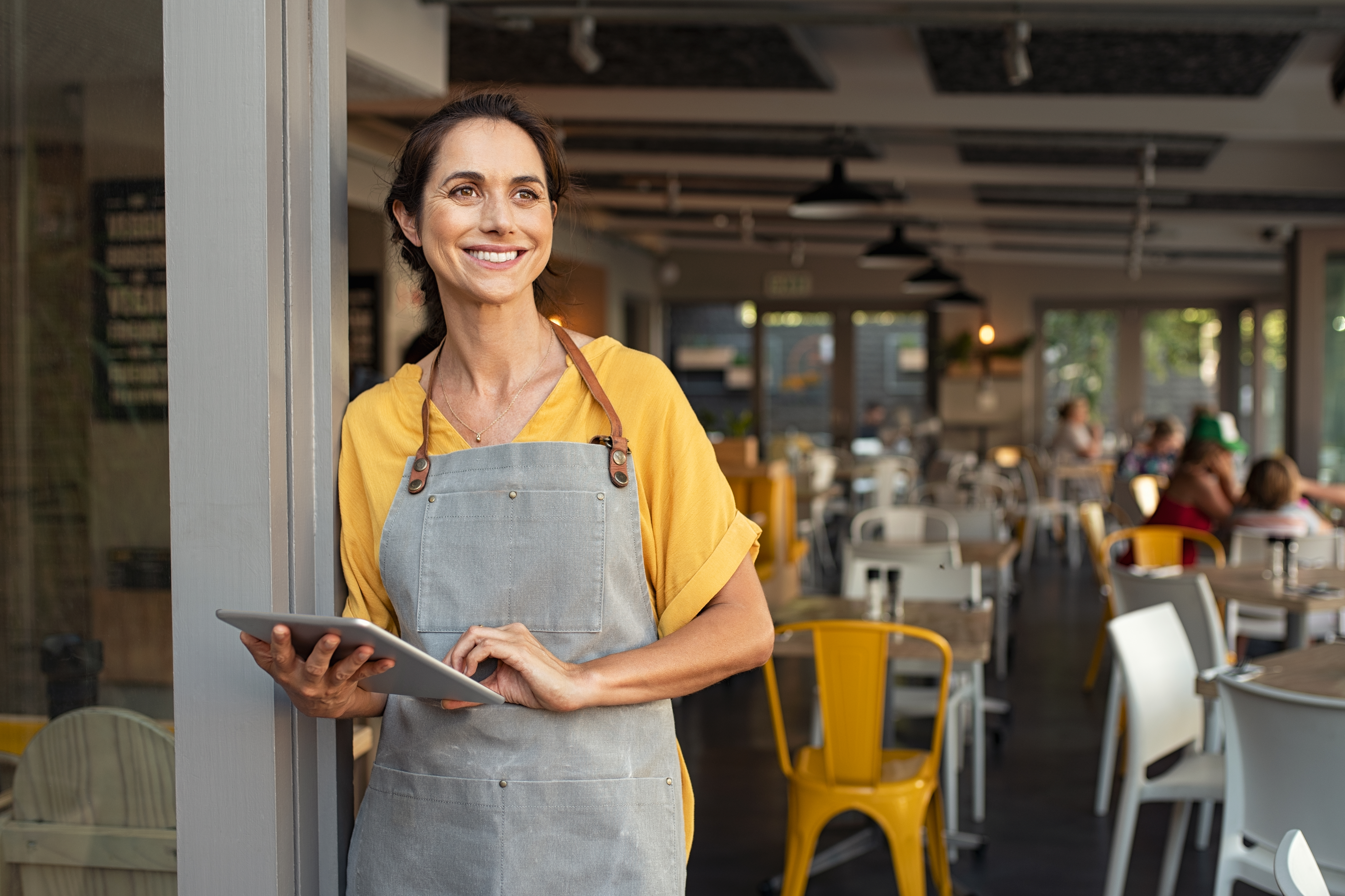 Smiling lady with apron outside a restaurant