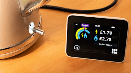 In-home display energy device on a table next to a kettle.