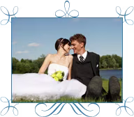 A bride and groom sitting by a lake.