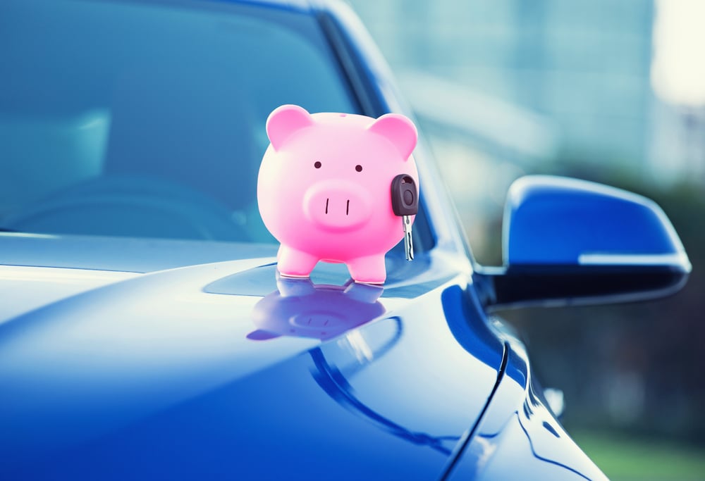 A piggy bank holding a key on a car