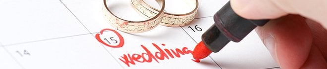 Someone is writing 'wedding' into the date 15 on a calendar with a red marker.