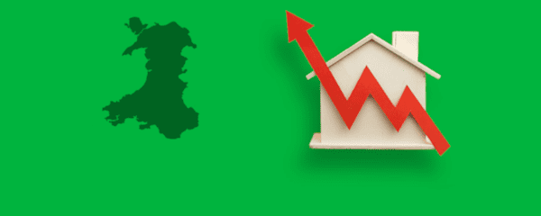Silhouette of Wales next to a model house with a red arrow trending upwards over it.