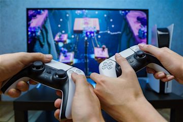 People with two gaming handsets playing games on a TV screen