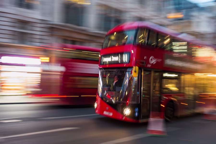 A red London bus, destination Liverpool Street. It's in motion and the background is blurred.