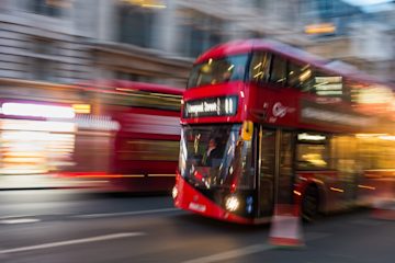 A red London bus, destination Liverpool Street. It's in motion and the background is blurred.