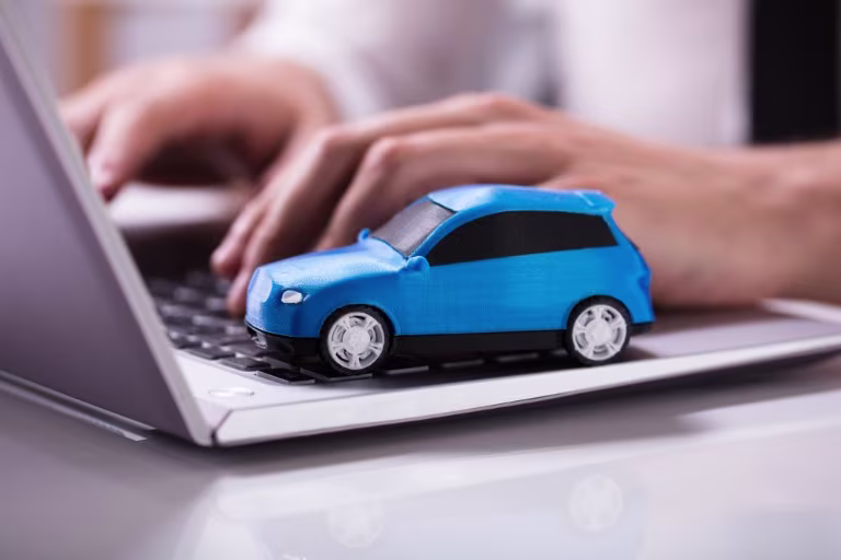 A blue toy car sitting on a laptop keyboard