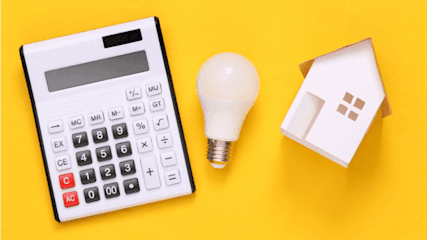 Image shows a white calculator, a white lightbulb and a model white house against a yellow background.