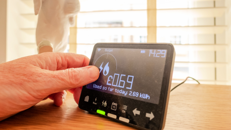 Hand reaching for in-home energy smart meter device on table.