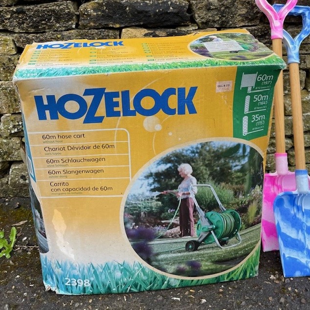 Image of a 'Hozelock' garden hoze wheel, left outside a house for passers by to take if they wish. Packet is bright yellow - the brand is hoze lock with a zee or zed