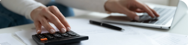 person typing on calculator and laptop computer