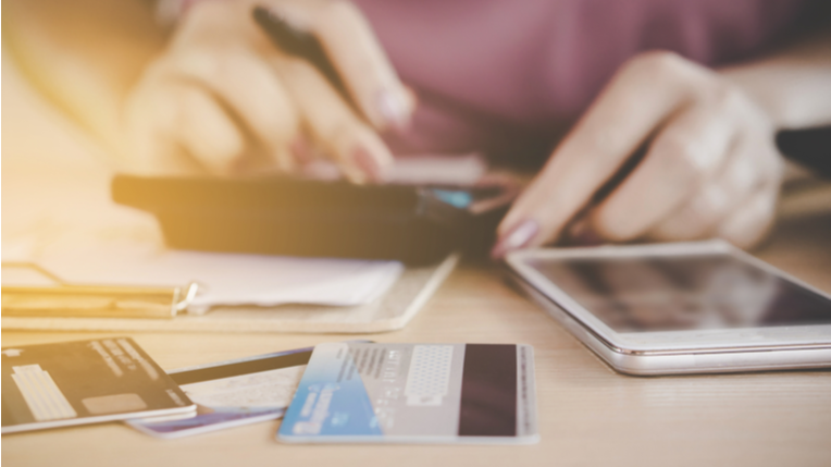 Person using a calculator, phone and credit card to work on their finances