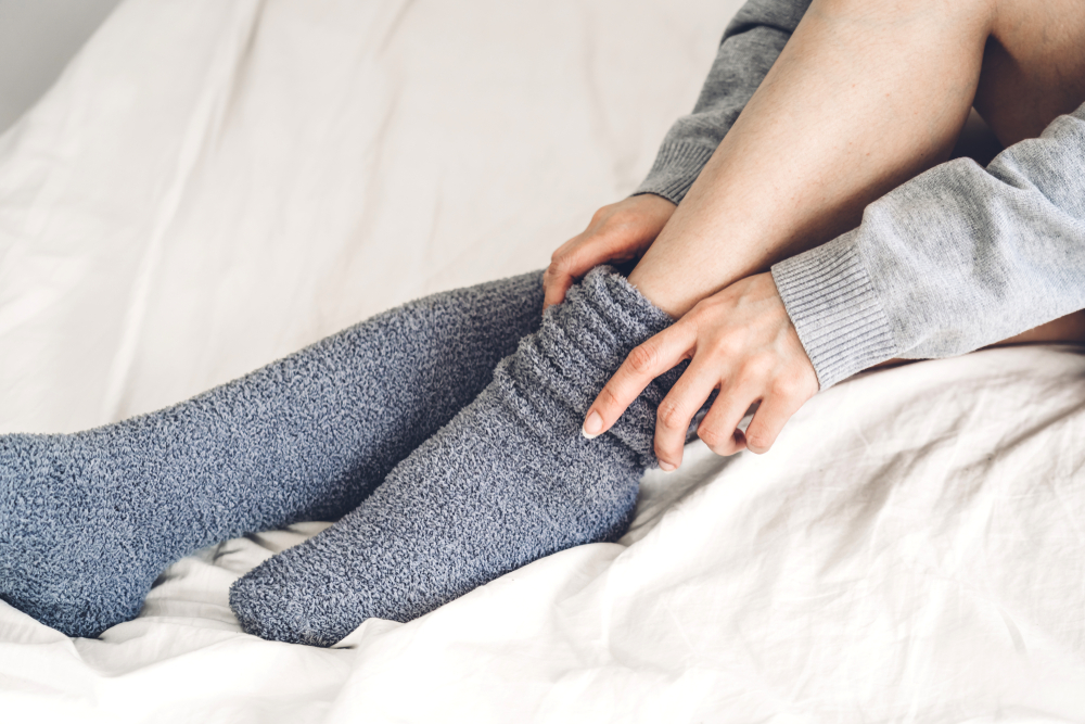Young woman putting on a pair of grey socks.