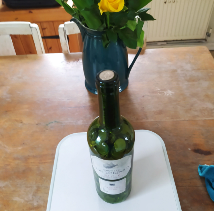 A wine bottle full of 5p coins, stood on a table