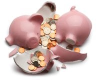 Broken pink piggy bank with gold coins spilling out and ceramic fragments scattered on white background