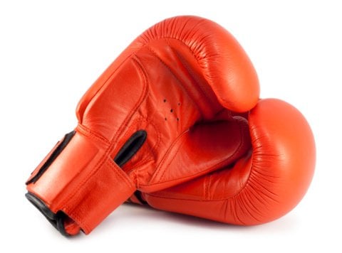 A pair of red boxing gloves, with the right one laying on top of the left.