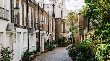 A row of white and red brick flats on a cobblestone street
